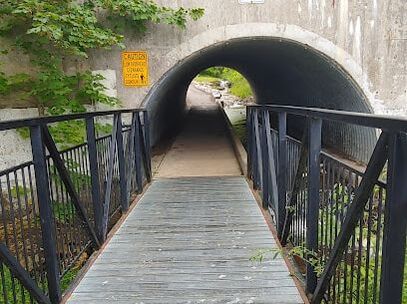 Wood bridge with black metal railings leading to a tunnel in Blair Road, Cambridge, Ontario